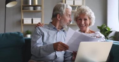 Mutlu yaşlı çift kağıtları kontrol ediyor faturaları ve laptopları tutuyor.
