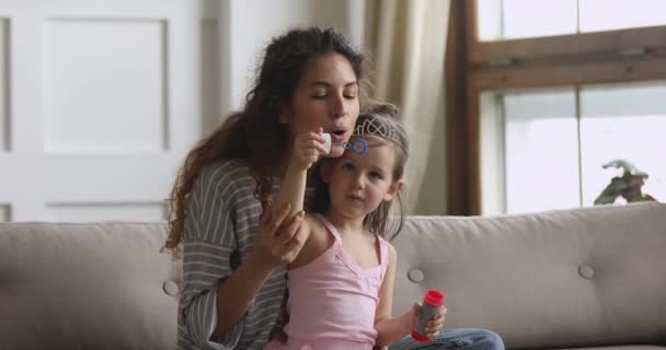 Счастливые мама и дочь пускают мыльные пузыри дома — стоковое видео
