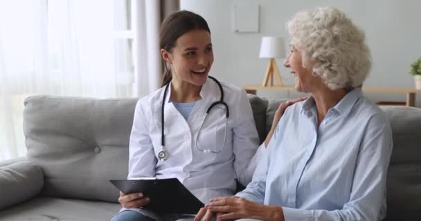 Opiekuńcza młoda pielęgniarka pomaga zachęcić starszą babcię pacjenta — Wideo stockowe