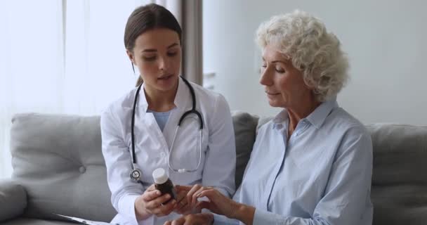 Jonge vrouwelijke arts voorschrijven geneeskunde aan oude grootmoeder patiënt — Stockvideo
