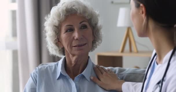 Старша старенька пацієнтка розмовляє з лікарем на консультації з огляду — стокове відео