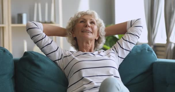 Glad avslappnad gammal kvinna vilar drömmande sitter på bekväm soffa — Stockvideo