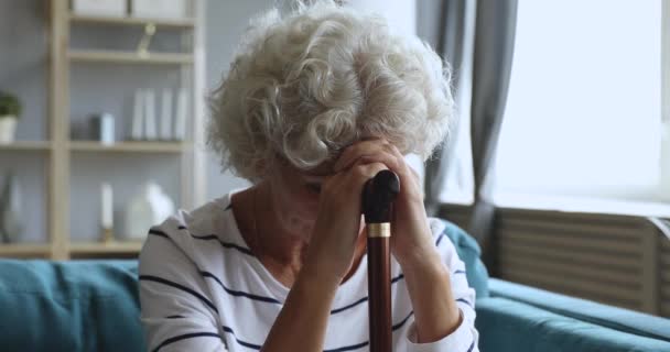 Triste cansada señora mayor mantenga bastón sentarse solo en el sofá — Vídeos de Stock