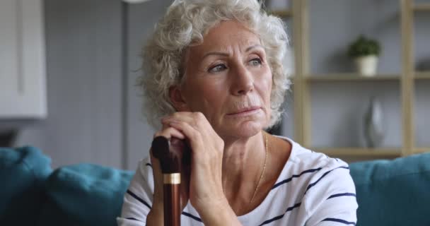Mulher idosa deprimida segurando bengala pé sentar no sofá — Vídeo de Stock