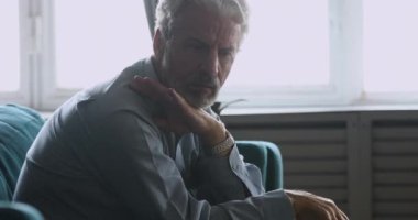 Üzgün kıdemli adam evde tek başına oturup üzülüyor.