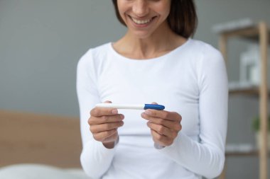 Gülümseyen milenyum melezi kadın elinde plastik bir test tutuyor..