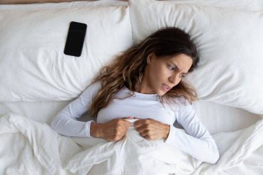 Sinirli milenyum melez kadın cep telefonu alarmından sonra uyanıyor..