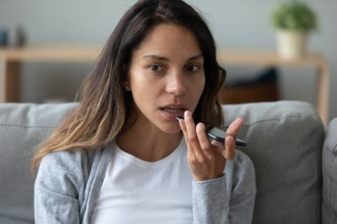 Cep telefonunda sanal asistan kullanan konsantre genç ırk hanımı..