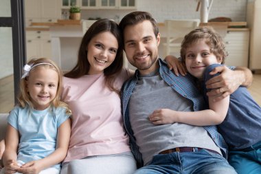 Mutlu bir aile portresi, küçük çocuklu bir aile evde sarılıyor.