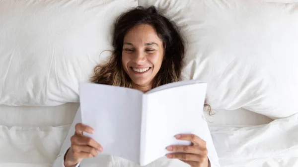 快乐的混血女青年喜欢在床上看书. — 图库照片