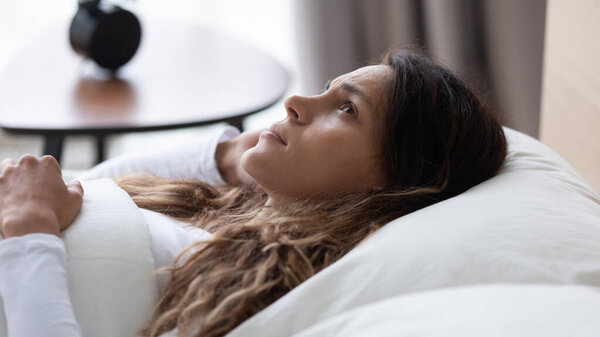 Несчастная задумчивая молодая расовая женщина лежит в постели
.