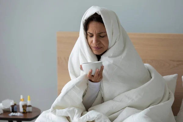 Нездоровая женщина страдает от замерзания, покрытая одеялом с головой . — стоковое фото