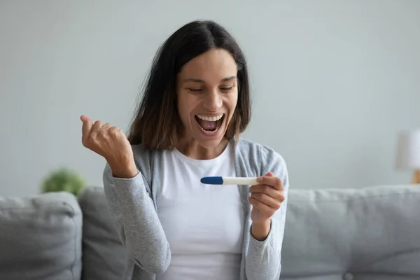 Overjoyed young mixed race girl looking at pregnancy confirmation test. — Stock Photo, Image