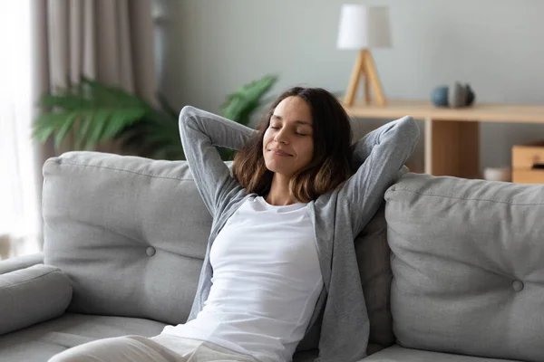 Senyum tenang birasial milenial wanita bersandar di sofa . — Stok Foto