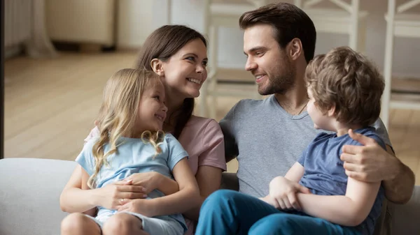 Lyckliga föräldrar med liten dotter och son sittande på soffan — Stockfoto