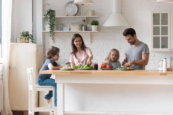 Küçük çocuklu mutlu bir aile birlikte salata hazırlıyor. — Stok fotoğraf