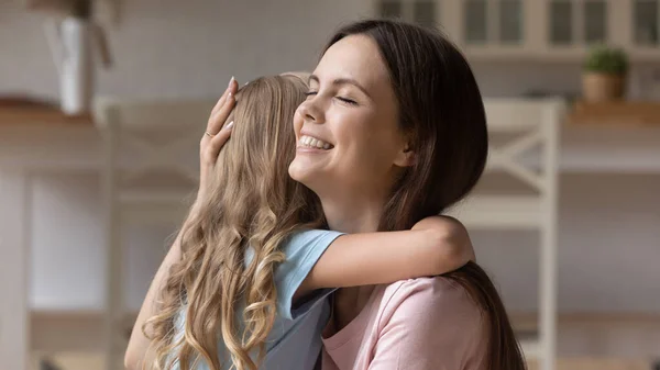 Leende mor kramar lilla dotter, uttrycker kärlek och stöd — Stockfoto