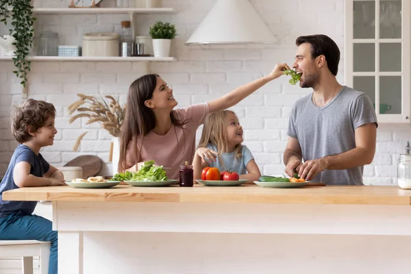 Glad familj matlagning sallad tillsammans, leende mor matande far — Stockfoto