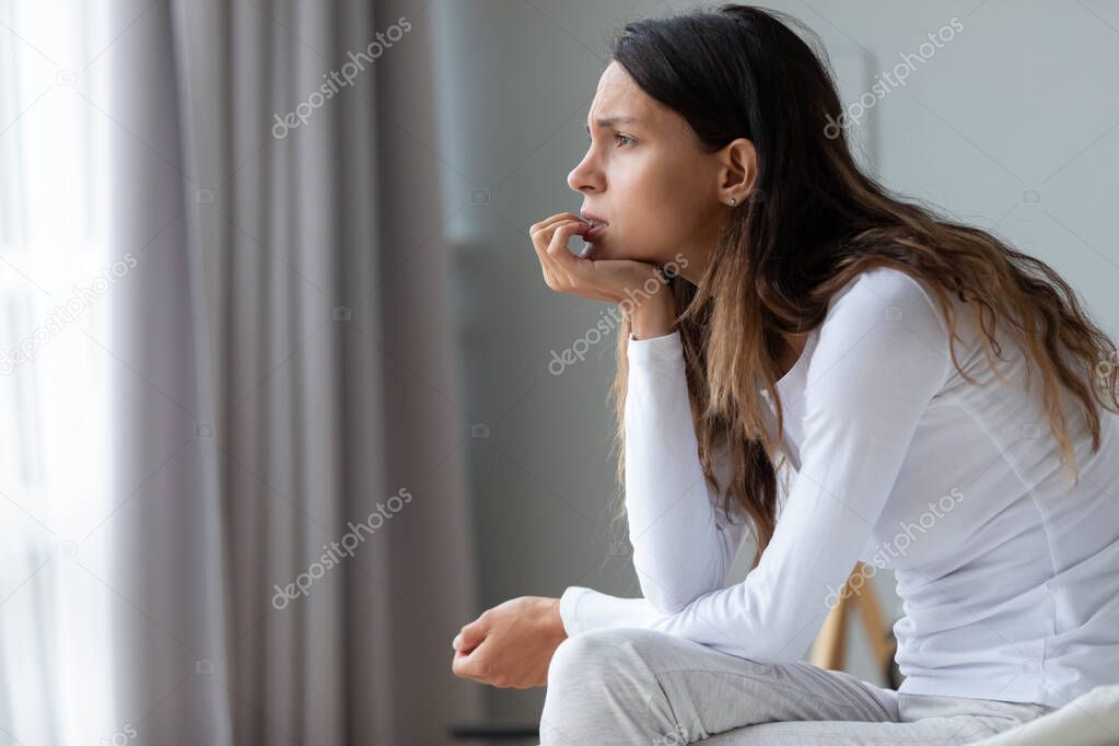 Confused anxious young mixed race woman biting nails.