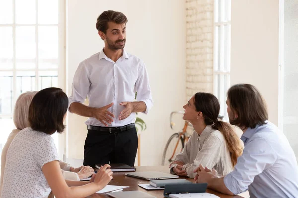 Confident male leader speaking to diverse team at office briefing