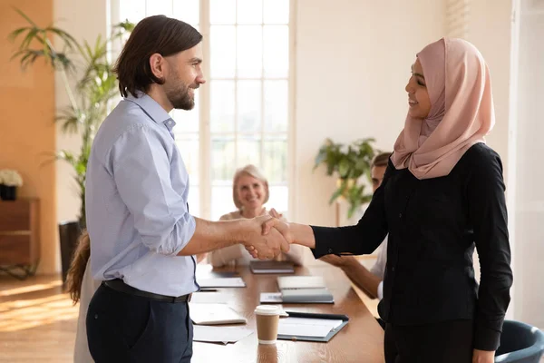 Gelukkig aziatische moslim vrouw werknemer krijgen bevorderd handdruk Kaukasische baas — Stockfoto