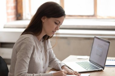 Yoğunlaşmış kız, masaya otur ve üniversite seansına hazırlan.