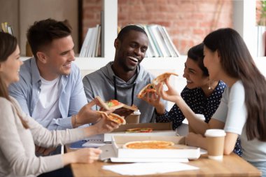 Çeşitli öğrenciler pizza yiyip sohbet ediyorlar, derslerine ara veriyorlar.