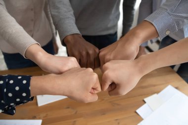 Diverse student touch fists hold together make circle as symbol of promises
