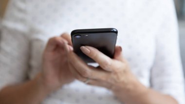 Üst düzey kadın akıllı telefonu cep telefonu uygulaması kullanarak tutuyor, görüntüyü kapat