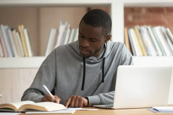 Amerikalı adam okul ödevlerini sınıf masasında yapıyor. — Stok fotoğraf