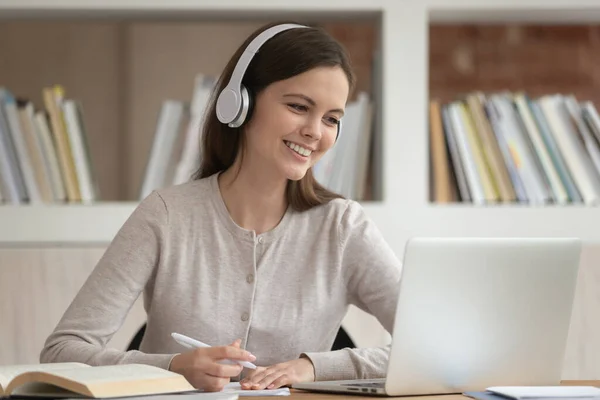 Dívka ve sluchátkách se dívá na obrazovku PC se studiem uvnitř — Stock fotografie