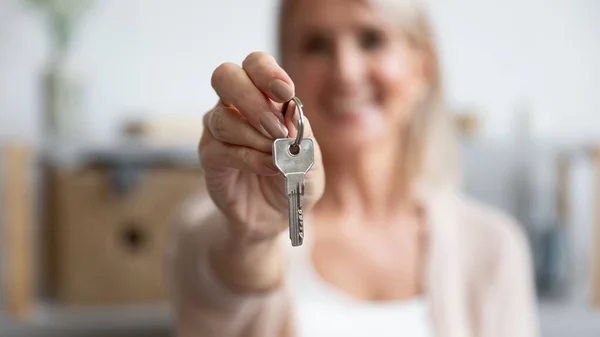 Zufriedene Seniorin hält Schlüssel für neues Haus, Nahaufnahme — Stockfoto