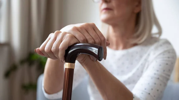 Anciana anciana sosteniendo bastón en las manos, de cerca — Foto de Stock