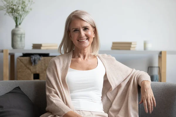 Feliz mujer de mediana edad mirando a la cámara en casa — Foto de Stock