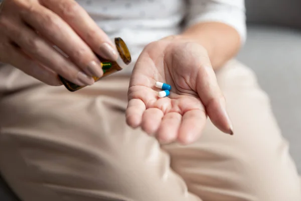 Senior woman holding pills capsules on hand, close up view — Stock Photo, Image