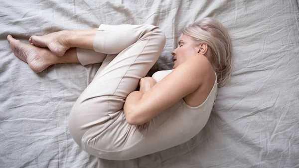 Wanita dewasa tertekan berbaring sendirian di tempat tidur dalam posisi janin — Stok Foto