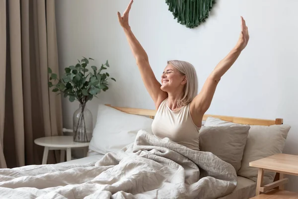 Yatakta uzanan mutlu olgun kadın mutlu bir şekilde uyanıyor. — Stok fotoğraf