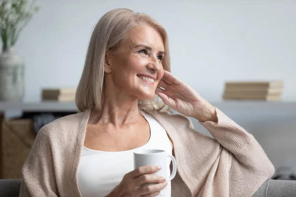 Felice sognante vecchia donna rilassante a casa bere caffè — Foto Stock