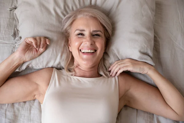 Glückliche ältere Frau wacht im Bett auf, Draufsicht — Stockfoto