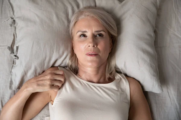 Middle aged woman insomniac lying awake in bed, top view — Stock Photo, Image