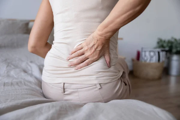 Oude volwassen vrouw zitten op bed touch terug voelen rugpijn — Stockfoto