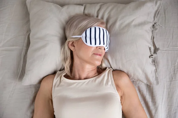 Calmo mulher velha gostando de dormir usar máscara de dormir na cama — Fotografia de Stock