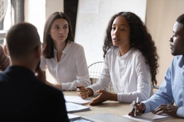 Genç Afrikalı iş kadını akıl hocası grup brifinginde çok ırklı insanlara ders veriyor.