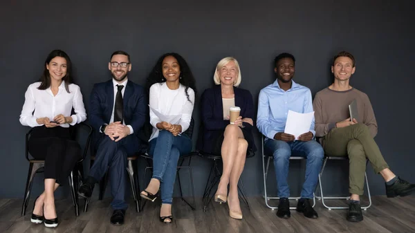 Smiling multiethnic professionals sit on chairs looking at camera — Stock Photo, Image