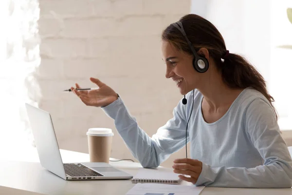 Χαμογελώντας millennial κυρία ελεύθερος επαγγελματίας φορώντας ακουστικά, επικοινωνώντας με τον πελάτη. — Φωτογραφία Αρχείου