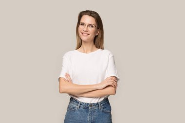 Kollarını kavuşturup poz veren gözlüklü, gülümseyen genç kadın.