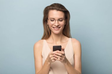 Gülümseyen milenyum kadını modern akıllı telefon interneti kullanıyor.