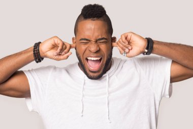 Deli Afrikalı Amerikalı adam gürültüden kaçınmak için kulaklarını tıkıyor.