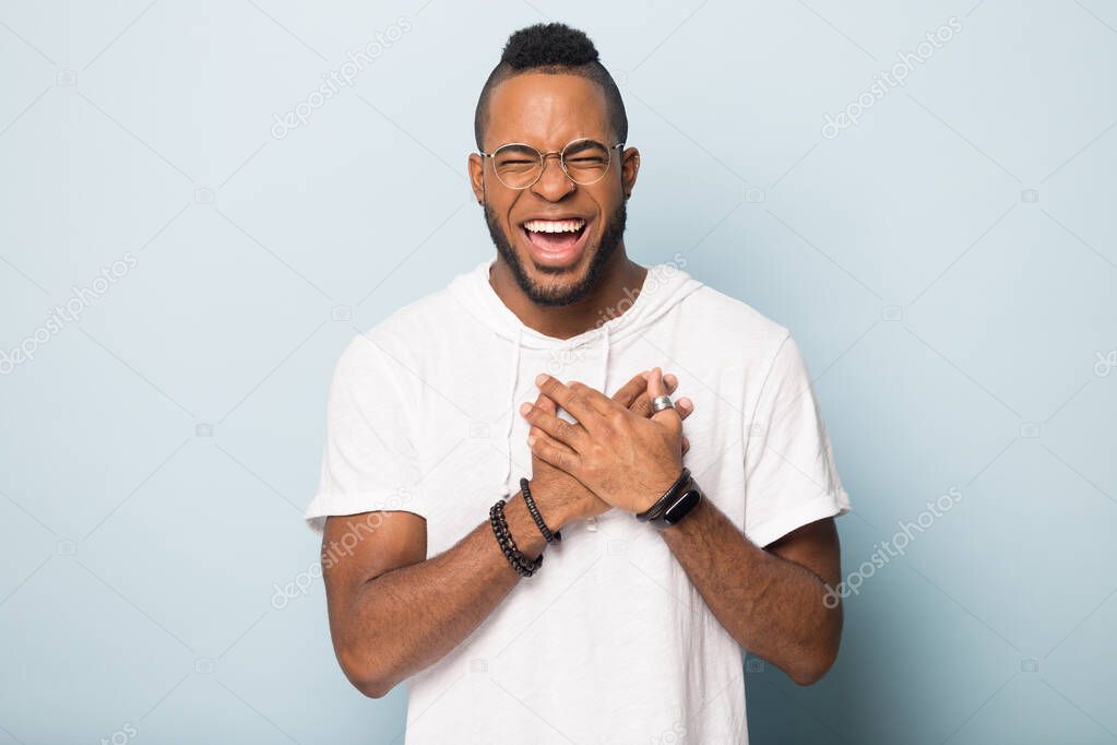 Happy african American man keep hands at chest laughing