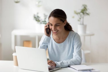 Genç mutlu karışık ırk serbest çalışanı müşterisiyle akıllı telefondan konuşuyor..